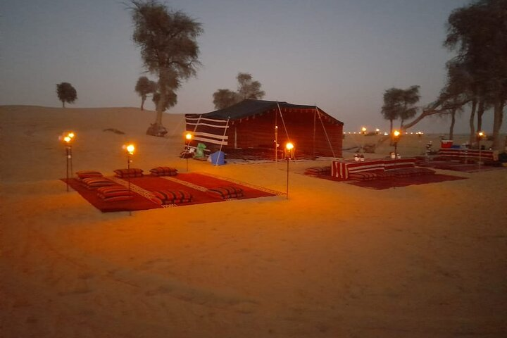 Experience a magical evening in the Dubai desert enjoying traditional cuisine and cultural activities as the sun sets over endless sand dunes creating memorable moments under the starry sky.